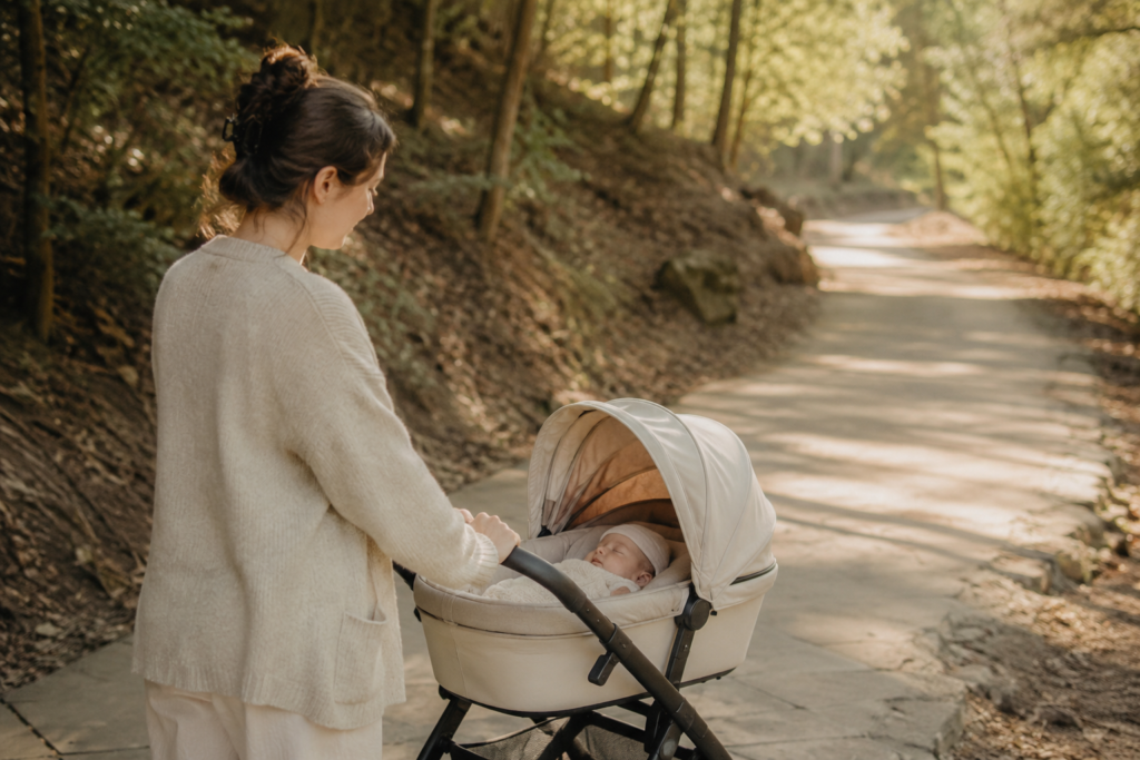 Mom taking a newborn for a short stroller walk as part of postpartum recovery.