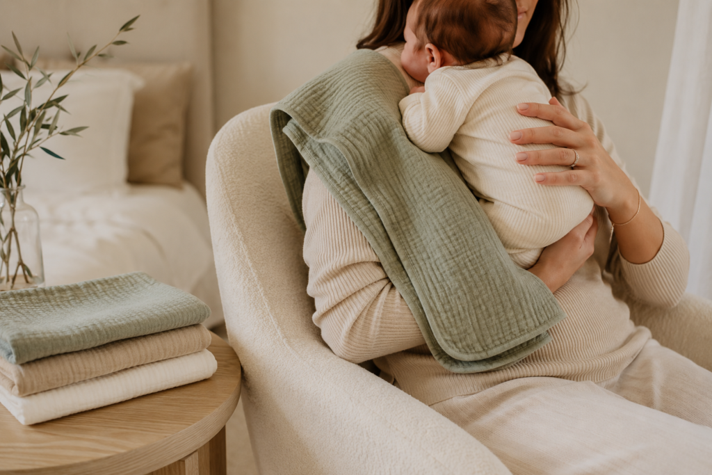 Newborn resting on mom’s shoulder with a muslin newborn burp cloths after feeding